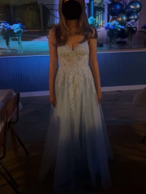 Ljusblå långklänning med spetsdetaljer  - Superfin ljusblå långklänning från JJ's House med tunna axelband, v-ringning och vackra spetsdetaljer. Kjolen är i flera lager tunn tyll. Snörning i ryggen för perfekt passform. Skriv till mig vid instresse om ni har några funderingar på mått osv. 