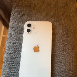 iPhone 12 - Snygg vit iPhone 12 med 85% batterihälsa. Dubbelkamera, 6,1-tums skärm och Face ID. Mindre slitage syns på ramen och en repa som du ser på bilden där bak men i övrigt fint skick. 