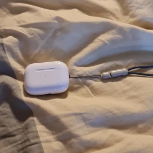 AirPods Pro (USB-C, 2nd generation) - Säljer ett par AirPods Pro (2nd gen) med USB-C-laddningsetui. Hörlurarna är i fint skick och levereras med handledsrem. Aktiv brusreducering och transparensläge. Inga synliga repor eller skador. Dem ljusen som skiner när du öppnar skalet kan du trycka på bak knappen sen försvinner dem i samma sekund den tråden som syns på bilden kommer med men inte laddare ANC funkar !