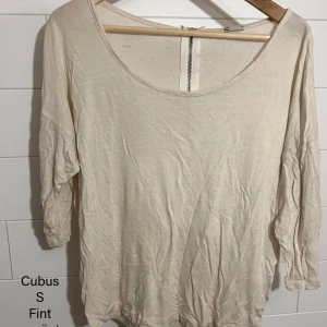 Beige långärmad tröja från Cubus - En enkel och stilren beige långärmad tröja från Cubus med rund halsringning och diskret dragkedjedetalj i nacken. Tillverkad i mjuk bomull, perfekt för en avslappnad look. Passar bra till jeans eller kjol.