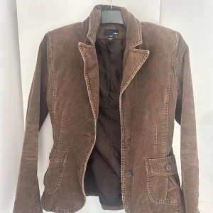 Höst / vår jacka! - Köpt på secondhand men har tyvärr gått upp i vikt så kan inte ha den längre. Men en snygg och tidlös kavaj/jacka i brun manchester från H&M. Modellen är figursydd med två framfickor med knappar och knäppning framtill. Hel fodrad med mörkbrunt innerfoder.