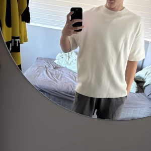 Oversized vit t-shirt i bomull - Säljer en oversized vit t-shirt med klassisk rund hals och korta ärmar. T-shirten är enkel och stilren, tillverkad i mjuk bomull som känns skön mot huden. Perfekt för dig som gillar en clean och avslappnad look. Lite större i modellen köpt från Zara.