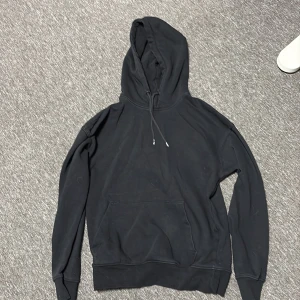 Svart hoodie från Jack & Jones - Svart hoodie från Jack & Jones med klassisk känguruficka och dragsko i huvan. Använd 2 gånger Ni står för frakt!