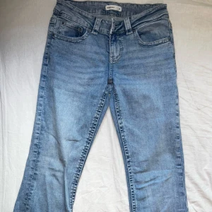 Ljusblå bootcut jeans från Gina tricot - Snygga ljusblå jeans från Gina tricot med bootcut-modell. Jeansen har medelhög midja, bälteshällor och knäppning fram. Bakfickorna har lock och knappdetalj som ger en cool touch. Perfekta till en avslappnad stil. Byxorna har knappt kommit till använding pågrund av storlek, därmed har jag behövt ta bilder från hemsidan på modellen. Byxorna är i mycket bra skick. Nypris: 499kr