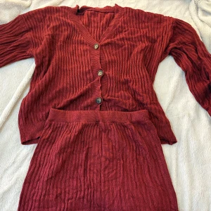 Vinrött ribbstickat set - En vinröd ribbstickad kofta tillsammans med en matchande kjol i samma färg och material. Settet är helt oanvänt och är i fint skick med mjukt och bekvämt material! PRIS GÅR ATT DISKUTERAS💕