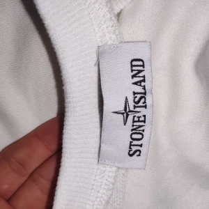 Vit långärmad tröja från Stone Island jätte fin helt ny pris kan diskuteras  - Vit långärmad tröja från Stone Island med klassisk rund hals och ikonisk logotyp-patch på ärmen. Tröjan är i mjuk bomull och har en stilren, enkel design som passar perfekt till streetwear-looken.