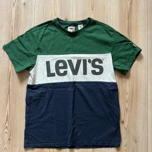 Levi's t-shirt i grönt, vitt och blått - S - Snygg t-shirt från Levi's i storlek S med breda blockränder i grönt, vitt och mörkblått. Stor logga framtill. Klassisk passform och rund hals. Tillverkad i mjuk bomull, perfekt för en chill och stilren look.