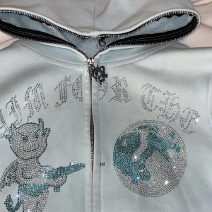 Ljusblå hoodie Aim For The Moon XS - Ljusblå hoodie med dragkedja från Aim For The Moon. Framsidan har glittriga stenar i silver och blått. Använt den max 3 gånger 