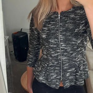 Svartvit topp/kofta från H&M  - Snygg svartvit topp/Kofta från H&M med stickad struktur och dragkedja framtill. Topp/kofta har en  rund halsringning, trekvartsärm och sen som en volang nertill. Mycket bra skick😊