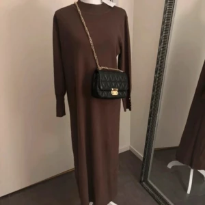 Brun lång klänning - Helt ny!  Klänningen är tillverkad i ett härligt material av viskos och polyester, vilket ger en mjuk och bekväm känsla.   Storlek: L/XL Längd: 130 cm