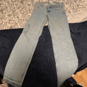 Weekday ljusblå jeans med patch - Ljusblå jeans från Weekday med raka ben, en extra ficka på benet och cool mörkblå patch på ena bakfickan. Jeansen har råa kanter nertill och klassisk femficksdesign. Perfekt för dig som gillar en unik och avslappnad stil. Köpt för 2 år sedan. Använd några gånger men sedan bara legat i garderoben. Ny pris ca 500kr mitt pris 200kr