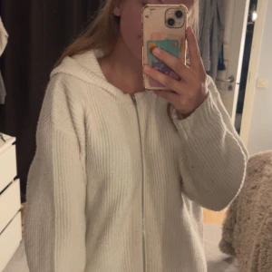 Vit ribbad hoodie från BikBok - Mysig vit hoodie från BikBok i storlek M. Tröjan är ribbstickad, har dragkedja framtill och en stor huva. Perfekt för kyliga dagar och enkel att matcha med jeans eller leggings.