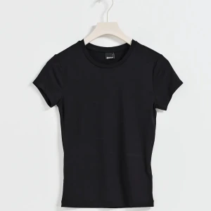 Svart basic t-shirt från Shein - Enkel svart t-shirt från Shein med rund hals och korta ärmar. Modellen är figurnära och tillverkad i mjuk bomull som känns skön mot huden. Perfekt att matcha med jeans eller kjol för en clean look.