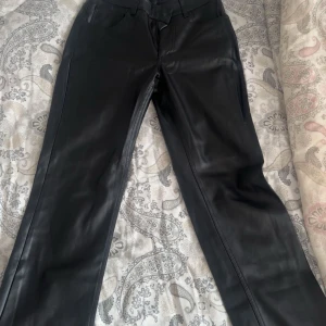 Svarta skinnbyxor från BikBok, strl 36 - Snygga svarta skinnbyxor från BikBok i storlek 36. Byxorna har raka ben, klassisk femficksdesign och dragkedja framtill. Materialet är mjukt och följsamt syntetläder med en matt finish. Perfekta för att lyfta din outfit med en edgy vibe. Saknar en knapp 