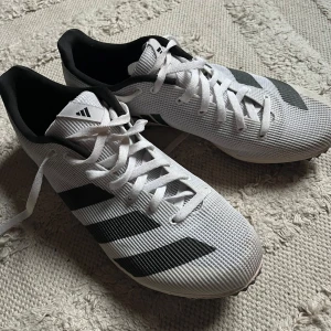 Adidas allround spikskor, vit och svart - Säljer ett par Adidas allround spikskor. Bra skick, storlek 39 1/3 