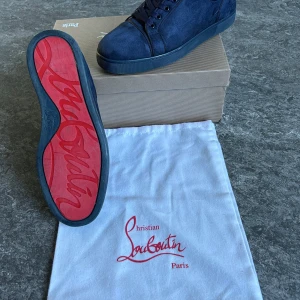 Mörkblå Louboutin skor - Snygga mörkblå sneakers från Christian Louboutin i mocka med klassisk röd sula. Box och dustbag ingår! Kan gå ner i pris vid snabb affär!