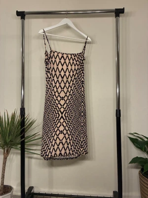 Kortklänning  - Snygg kortklänning från Sisters Point i beige och svart med ett grafiskt rutmönster. Klänningen har smala axelband och en lätt figurnära passform. Materialet är mjukt och känns som silke. Finns 2st  för dig och bästis eller bara en backup. OANVÄND 