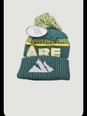 Åre mössa - Bilden visar ingen väst, utan en grön mössa med gul text och vit bergsbrodyr. Skriv vid minsta lilla fråga. Pris ej hugget i Sten 🪨