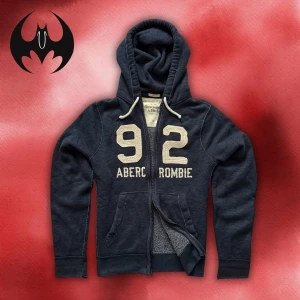 Blå Abercrombie & Fitch hoodie med dragkedja - Blå hoodie med dragkedja med vit markerad text ’92 Abercrombie’ och lite slitna, titta bilder | fint skick | size L / XL | Längd: 72cm Arm: 74cm Axelbredd: 48cm | Modell 162cm, 60kg