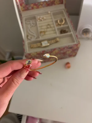 Guldarmband Caroline Svedbom - Snyggt guldarmband drop petite bracelet från Caroline Svedbom med två glittrande kristaller i ändarna. Armbandet är öppet och har en tunn, elegant form som passar perfekt till din smyckeskollektion. Kristallerna har en skimrande effekt som fångar ljuset superfint.