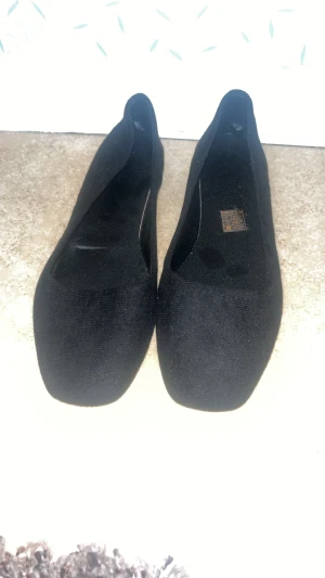 Svarta ballerinaskor med rund tå - Säljer ett par svarta ballerinaskor från Marco Tozzi med rund tå och platt sula. Skorna är gjorda i ett mjukt tygmaterial som ger en stilren och enkel look. Perfekta att slänga på sig när du vill ha något bekvämt och snyggt.