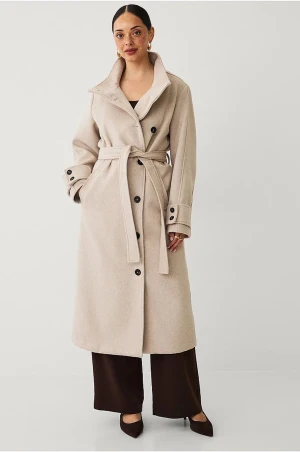 Beige kappa med bälte och knappar - Stilren beige kappa i ullmix med markerad krage, knappar framtill och bälte i midjan. Lång modell med snygga detaljer vid ärmslut och fickor på sidorna. Perfekt för dig som vill ha en klassisk och tidlös look.