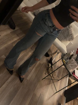 Blå lågmidjade bootcut jeans med slitningar - Snygga blå lågmidjade bootcut jeans med slitningar på låret och knät. 