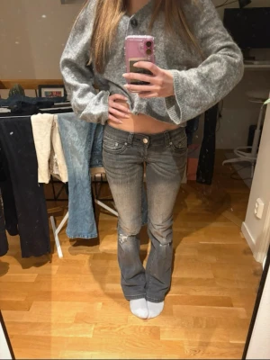 Grå bootcut jeans med slitningar - Säljer ett par grå bootcut jeans med låg midja och slitningar vid knäna. Från G rise i storlek S regular!