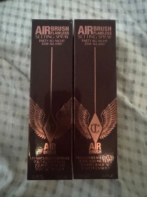 Charlotte Tilbury Airbrush Setting Spray - Charlotte Tilbury Airbrush Flawless Setting Spray i elegant mörkbrun förpackning med roségulddetaljer och vingar. Perfekt för att fixera makeup hela dagen och natten. Lyxig design och ikonisk logga på sidan av kartongen. Man kan få båda för 780 eller en för 390 