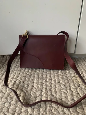 ATP ATELIER - Färg: Bourgogne/Bourgavillia Klassisk, tidlös design från ATP Atelier i högkvalitativt läder. Väskan är helt oanvänd och i perfekt skick.  Extra: Finns även matchande skor från ATP Atelier i annan annons. Perfekt för dig som vill ha stil och kvalitet i ett paket!