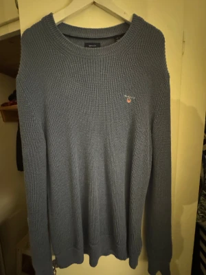 Blå stickad tröja från GANT - Säljer blå stickad tröja från GANT i storlek M (L/XL). Den är tvättad o tumlad och blivit större och därmed uttänjd. Passar en som har L/XL bättre än M.