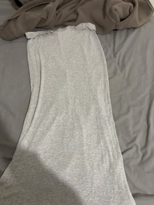 Grå kjol med slit  - En fin lång  grå kjol med slit, den är storlek L men passar även M. Den är från lager 157. Den är lite sönder vid sliten men det syns inte så mycket 
