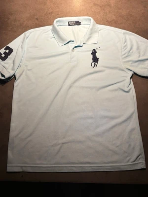 Ralph Lauren Pike - Säljer en riktigt snygg, modern och stilren ljusblå pike från Ralph Lauren. Storleken: L men är liten i storlek( M). Skriv vid frågor eller kom med bud!