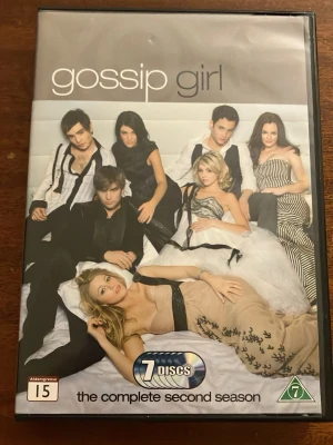 Gossip Girl säsong 2 DVD-box - Säljer Gossip Girl: The Complete Second Season på DVD. Boxen innehåller 7 skivor med hela säsong 2 av den populära dramaserien. Omslaget har en bild på huvudkaraktärerna och information på flera språk. Perfekt för dig som gillar ungdomsdrama och intriger. Skivorna är i mycket bra skick men dom är ej funktionstestade