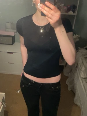 Svart croppad topp med kort ärm - En enkel och stilren svart croppad topp med rund halsringning och korta ärmar. Perfekt att matcha med jeans eller kjol för en clean look. Materialet känns mjukt och stretchigt.