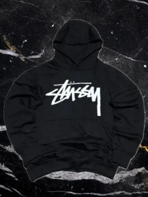 Stussy hoodie - Säljer denna snygga Stussy tröjan. ✅ Mycket gott skick, inga skador. ✅ Trycket är intakt och sprickfritt. ✅ Snyggt snitt. Etiketten säger storlek L, men den passar mer som en 160cm skulle jag säga. Använd gärna måtten nere!  Mått: Längd: 59 cm Bredd: 49 cm Ärmlängd från hals: 64 cm. Kan gå ner i pris vid snabb affär!
