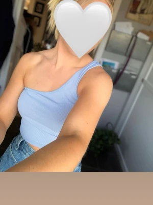 Ljusblå one shoulder topp från SHEIN - Trendig ljusblå ribbad topp från SHEIN med one shoulder-design. Croppad modell som sitter snyggt och är perfekt till jeans eller kjol. Tillverkad i mjukt och stretchigt material för en bekväm passform.