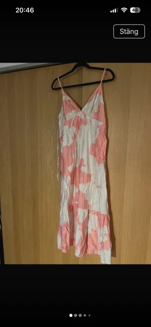 Klänning H&M strl M - Supersöt långklänning med v-ringning. Klänningen har ett stort blommigt mönster i rosa och vitt, samt volang nedtill. Tillverkad i en mjuk mix av viskos och polyester, perfekt för varma dagar. Tunnare i materialet