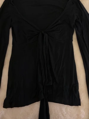 Svart långärmad topp Design by Si - Säljer en svart långärmad topp från Design by Si i storlek XS/S. Toppen har en snygg knytning framtill