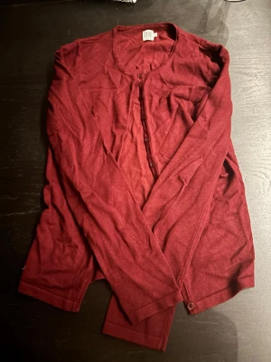 Vinröd kofta från Saint Tropez - Snygg vinröd kofta från Saint Tropez med rund halsringning och knäppning framtill. Långärmad och i ett mjukt, tunt material som känns skönt mot huden. Perfekt att slänga över en t-shirt eller linne för en chill look.