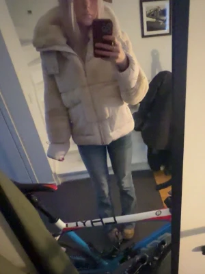 Beige pufferjacka med stor krage - Säljer en beige pufferjacka med stor, mysig krage och quiltad design. Jag har aldrig använt jackan då jag fick den för flera år sen i julklapp å glömt att den finns. Jackan har en oversized passform och långa ärmar, perfekt för kalla dagar. Enkel dragkedja framtill och stora fickor på sidorna. Man kan även dra upp dragkedjan hela vägen och då blir den super mysig speciellt om man har de så och luvan på. Superstylish och bekväm för vintern.