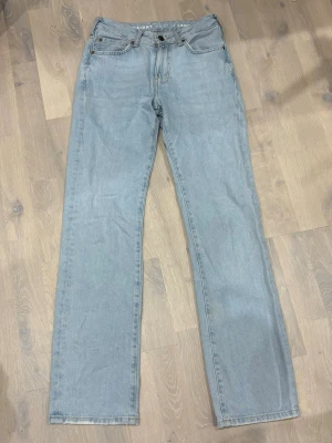Ljusblå raka jeans mid waist - Snygga ljusblå jeans med rak passform och mid waist. Klassisk femficksmodell med knappgylf och bälteshällor. Perfekta till en avslappnad stil och tillverkade i mjukt jeanstyg.