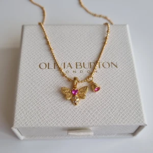 Guldigt halsband fjäril - Superfint halsband i guldton med en detaljerad fjärilsberlock och en liten bikupa, båda med rosa stenar. Kedjan har små kulor för extra detalj. Perfekt för dig som gillar söta och unika smycken med färgklick. Lådan ingår ej.