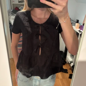 Svart blus med snörning fram - Säljer en svart blus från Gina tricot med korta ärmar och snygg snörning framtill.