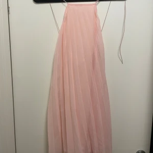 Ljusrosa klänning från NA-KD - Superfin ljusrosa klänning från NA-KD med tunna axelband och korsad i ryggen. Aldrig använd. 