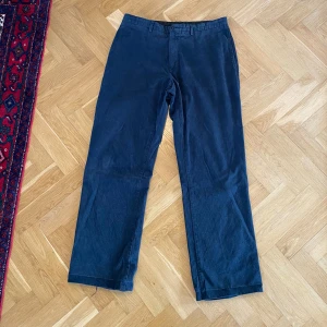 Mörkblå manchesterbyxor med raka ben - Snygga mörkblå manchesterbyxor med raka ben och klassisk passform. Byxorna har bälteshällor, sidfickor och bakfickor med knapp. Materialet är mjukt och ger en cool vintagekänsla. Perfekta för dig som gillar retrostil och vill ha något bekvämt och stilrent. Slitage i hälen, även insydda vid midjan. Storlek är 32/32
