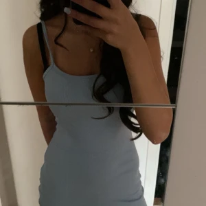 Ljusblå ribbad kortklänning - Säljer en ljusblå, ribbad kortklänning med smala axelband och figurnära passform. Klänningen har en enkel och stilren design som framhäver siluetten. Perfekt för dig som gillar minimalistisk och fräsch stil.