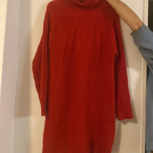 Röd stickad klänning från KappAhl XS - Mysig röd stickad klänning från KappAhl i storlek XS. Klänningen har polokrage, lång ärm och ett snyggt flätstickat mönster upptill. Perfekt för kalla dagar när du vill vara både varm och snygg eller något festlig tillfälle som julafton