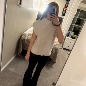 Beige stickad polotröja  - Säljer denna super snygga beige stickade polotröjan med ärmlös design och hög krage. Toppen har en mjuk och mysig känsla. Säljer då den inte kommer till användning. Använd väldigt få gånger och ser oanvänd ut. Köptes ny för 700kr. Passar S/M