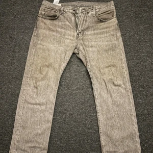 Levi's 551z grå jeans W32 L30 - Snygga grå Levi's 551 jeans med klassisk femficksdesign och raka ben. Jeansen har en cool, lite tvättad look och är tillverkade i slitstarkt denim. Perfekta för dig som gillar en avslappnad och tidlös stil. Märkespatch bak i midjan och ikonisk röd Levi's-tagg på bakfickan. Så gott som nya